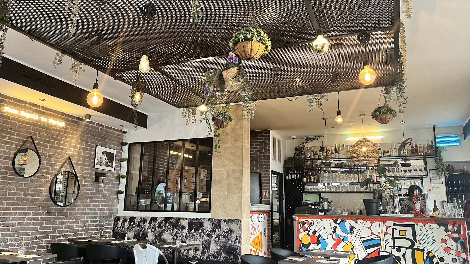 Salle actuelle du restaurant Al Solito Posto avec son bar et ses suspensions végétales